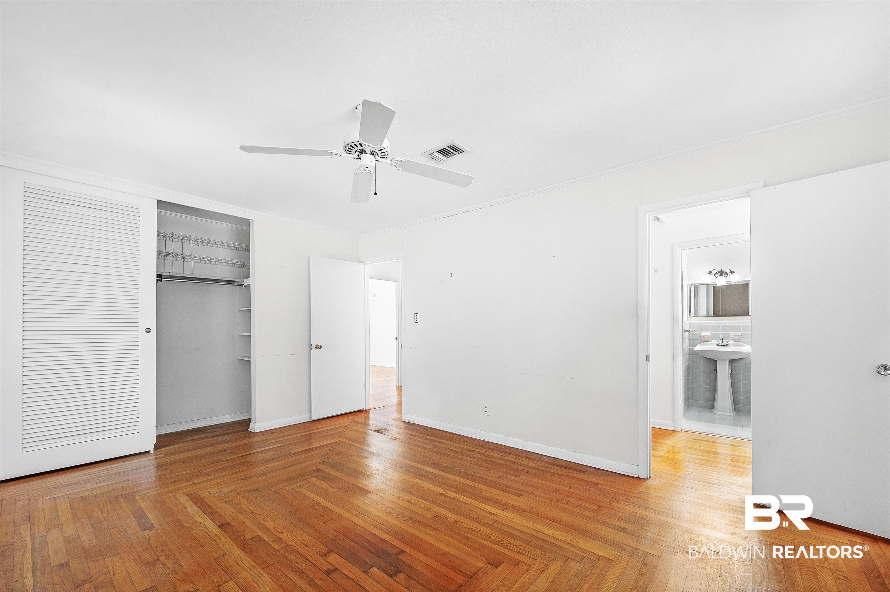 14375 Oak Street Magnolia Springs, AL 36555 - Photo 17 of 20 Unfurnished bedroom with cottage patterned oak hardwood floor, ceiling fan, sink, and a closet