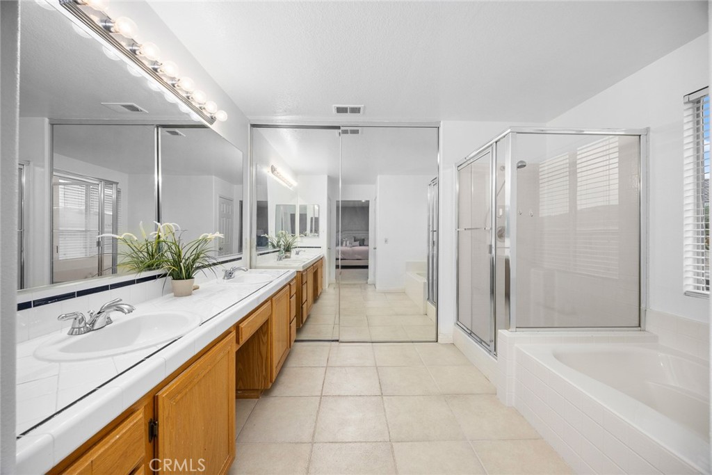 7343 Legacy Place Rancho Cucamonga, CA 91730 - Photo 27 of 53 a bathroom with a granite countertop sink a mirror a bathtub and shower
