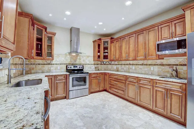 a kitchen with granite countertop wooden cabinets stainless steel appliances and a sink