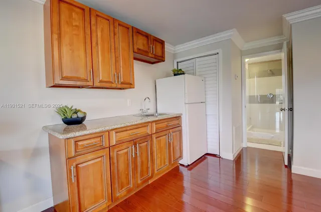 a kitchen with stainless steel appliances granite countertop a refrigerator a sink and white cabinets with wooden floor