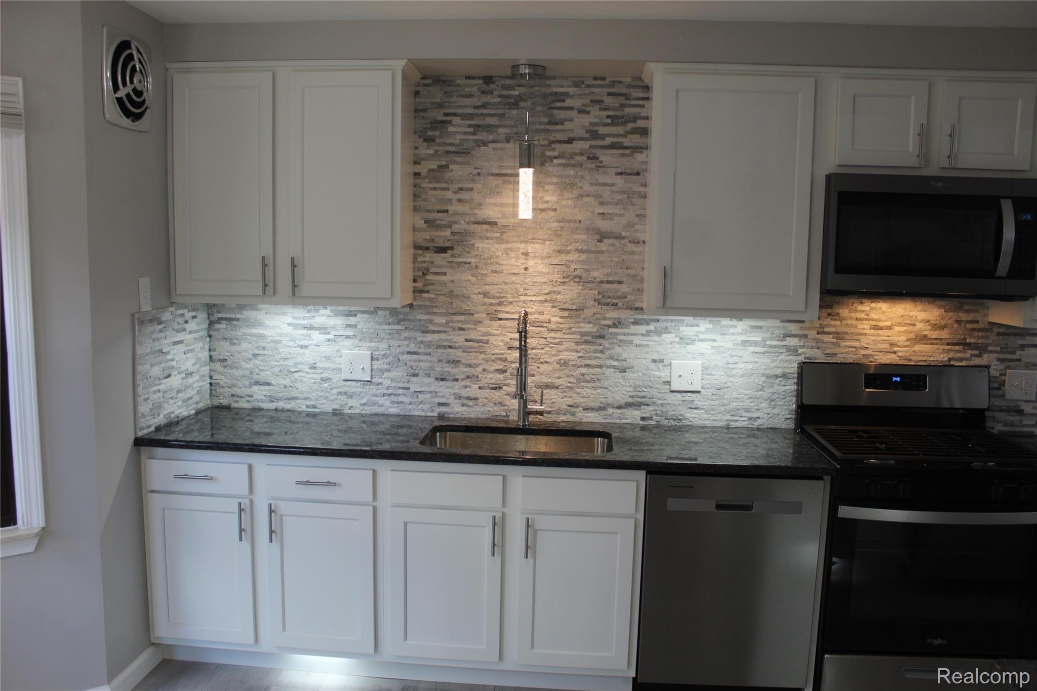 5543 Balfour Road Detroit, MI 48224 - Photo 6 of 54 White cabinetry with brushed nickel hardware, black countertops, and a full tile backsplash