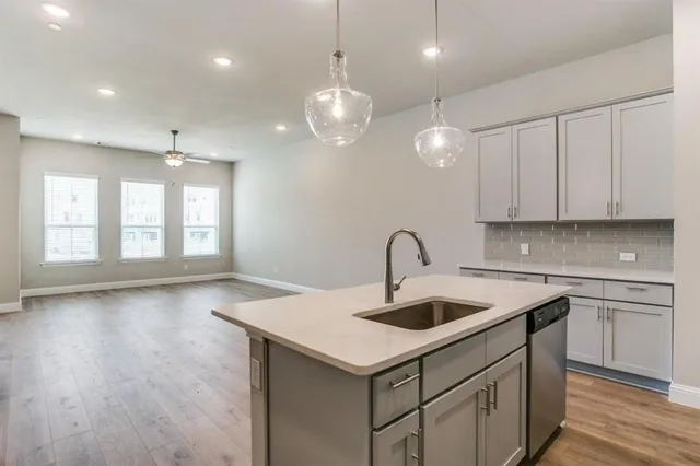 a kitchen with a sink a chandelier stainless steel appliances and cabinets