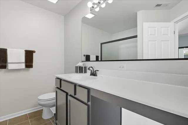 a bathroom with a granite countertop sink a toilet and a mirror