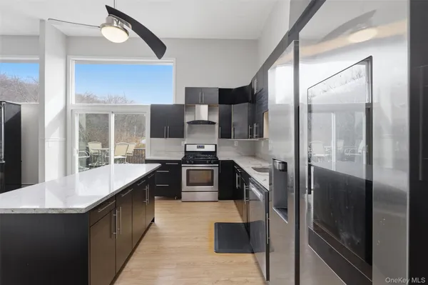 a large kitchen with stainless steel appliances kitchen island granite countertop a refrigerator a stove and a sink