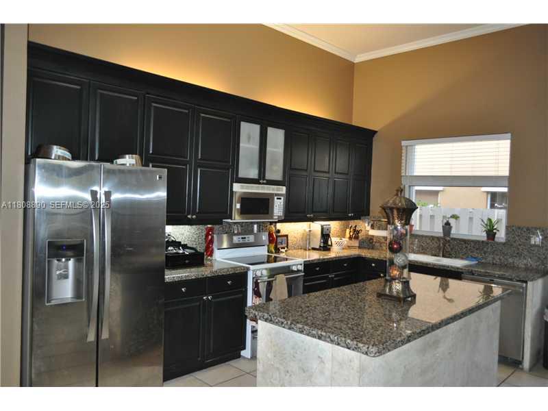 3985 Southwest 152nd Avenue Miramar, FL 33027 - Photo 12 of 26 a kitchen with stainless steel appliances granite countertop a sink refrigerator and cabinets