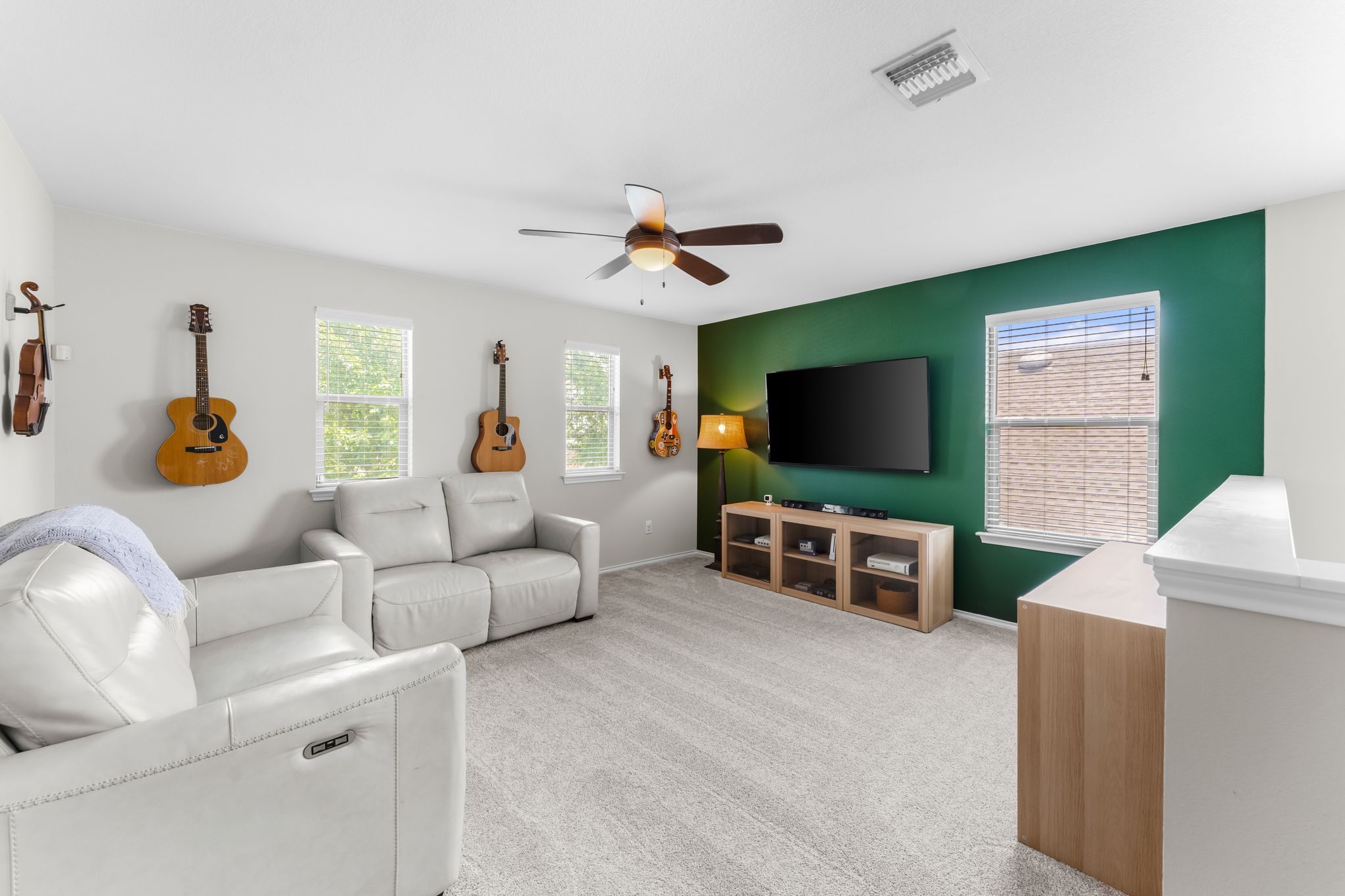 1133 Yellow Iris Road Leander, TX 78641 - Photo 14 of 37 Carpeted bonus room featuring a ceiling fan, multiple windows, a dedicated accent wall, and a low wall partition