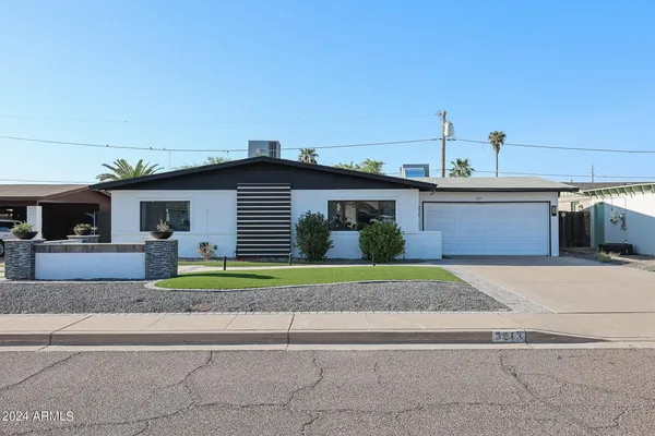a front view of a house with a yard and potted plants