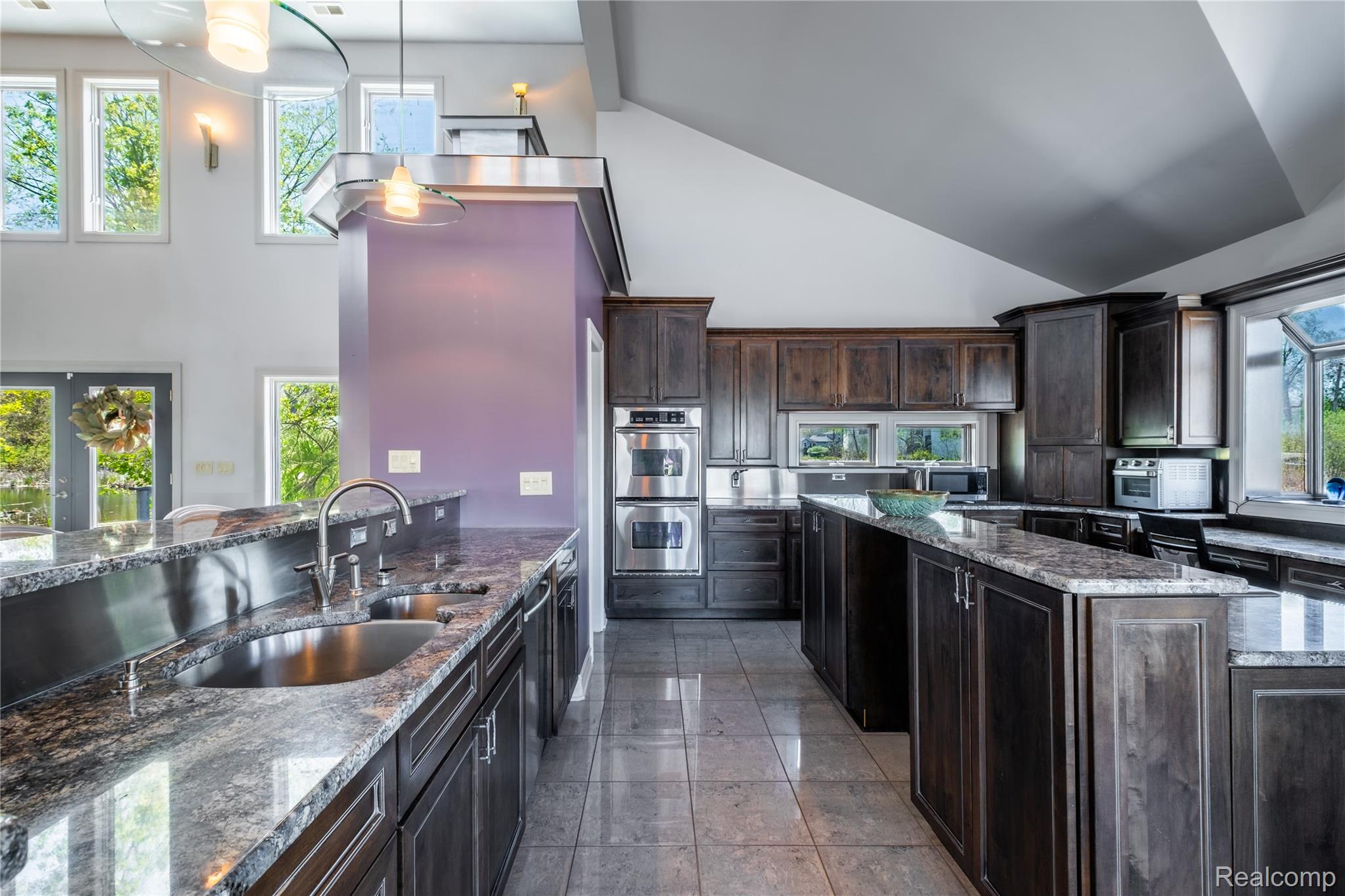 2350 Crane Road Fenton, MI 48430 - Photo 14 of 58 Kitchen featuring a kitchen island, dark stone counters, dark wood finish cabinetry, double oven, and decorative light fixtures