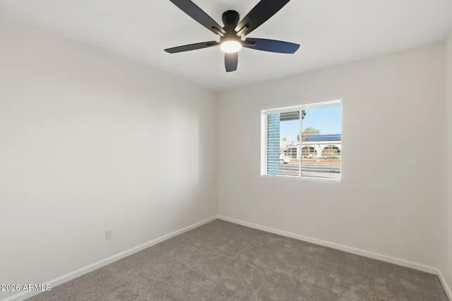 an empty room with a window and a fan