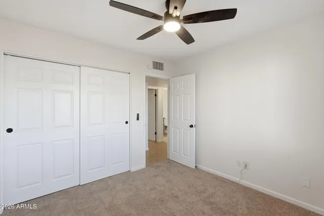 an empty room with closet and a chandelier fan