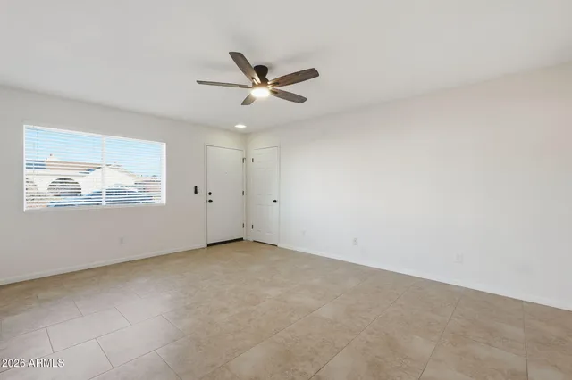 an empty room with window and ceiling fan