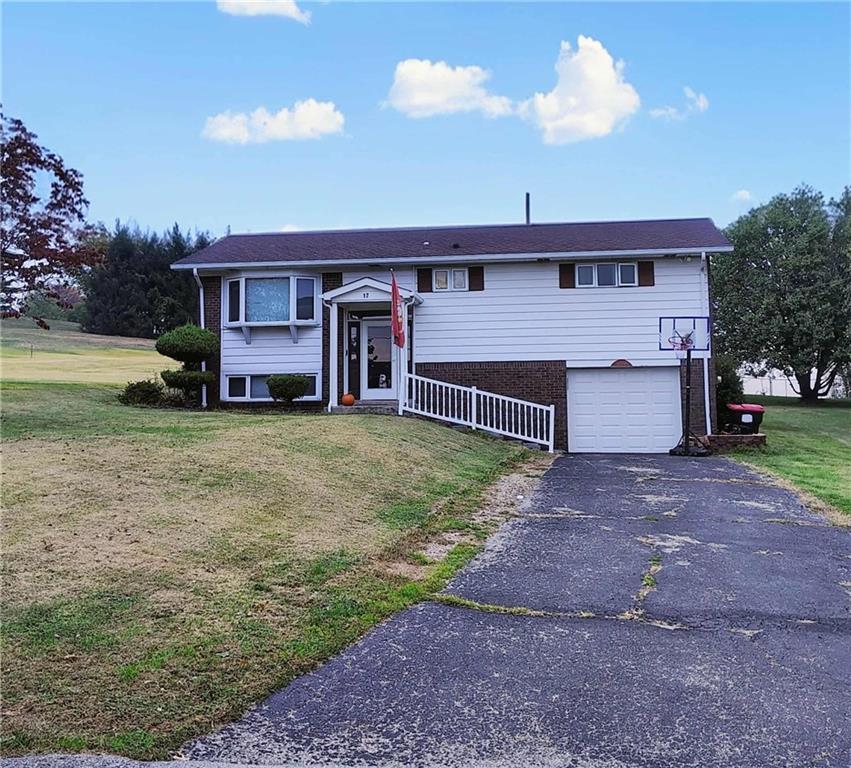 a view of a house with a yard and a large tree
