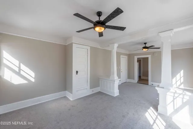 a view of an empty room with window and ceiling fan