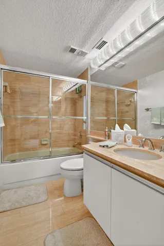 a bathroom with a granite countertop sink a toilet and shower