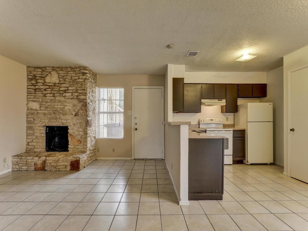 4300 Acropolis Court, Unit A Austin, TX 78759 - Photo 3 of 14 Kitchen featuring light countertops, white appliances, a textured ceiling, dark wood finish cabinets, and a fireplace