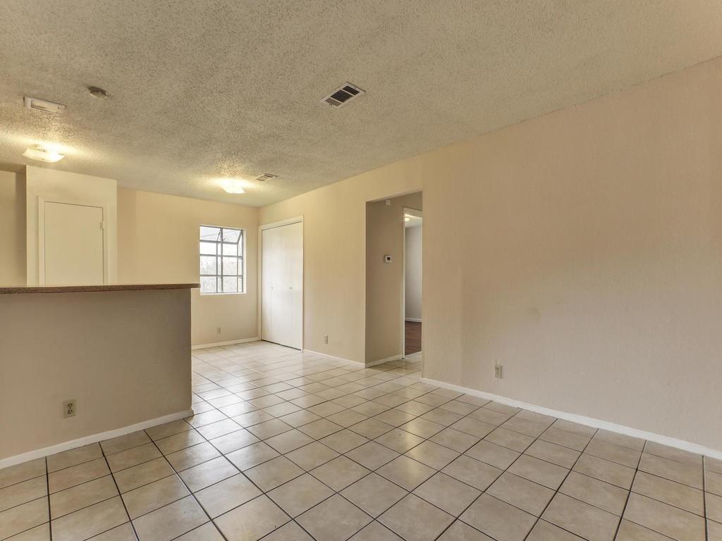 4300 Acropolis Court, Unit A Austin, TX 78759 - Photo 5 of 14 Empty room with a textured ceiling and light tile patterned floors