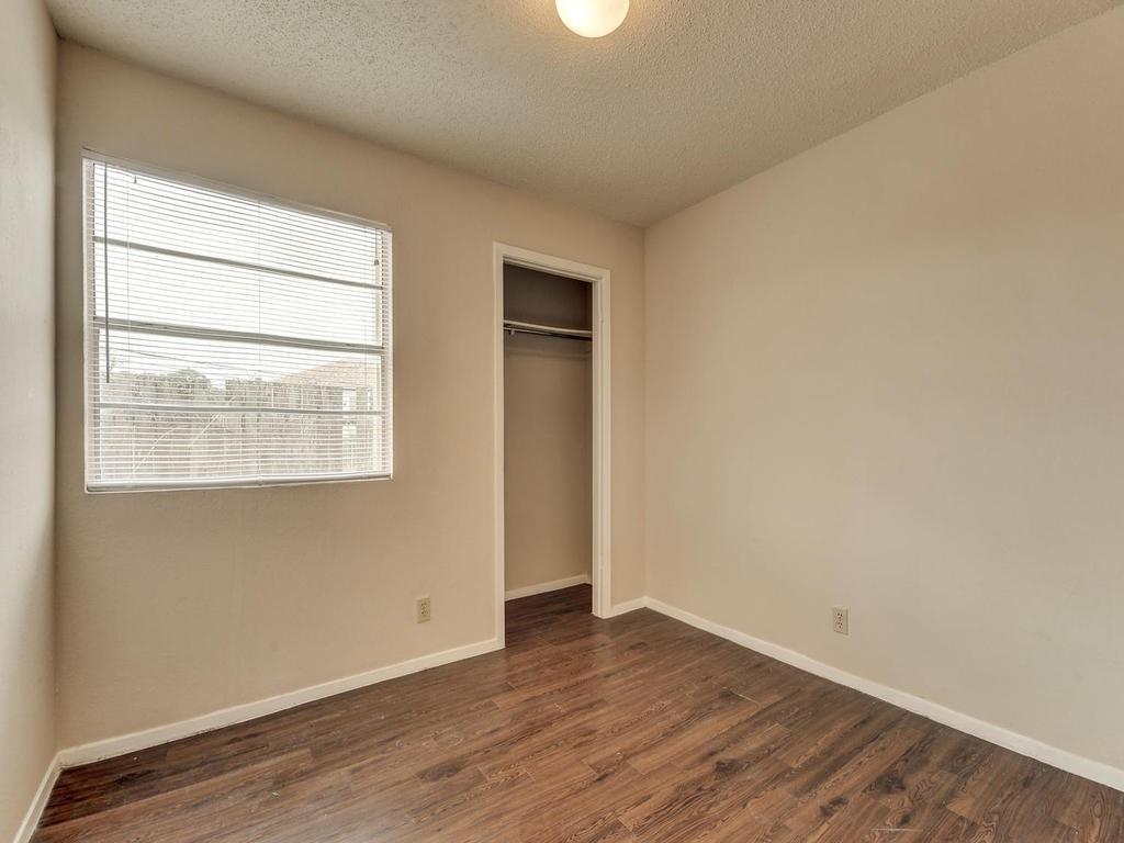 4300 Acropolis Court, Unit A Austin, TX 78759 - Photo 8 of 14 Unfurnished bedroom with dark wood finished floors, a textured ceiling, and a closet