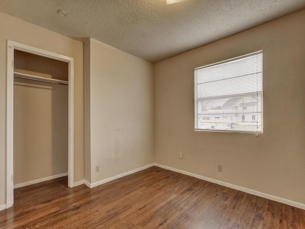 4300 Acropolis Court, Unit A Austin, TX 78759 - Photo 10 of 14 Unfurnished bedroom with a textured ceiling, dark wood-style flooring, and a closet