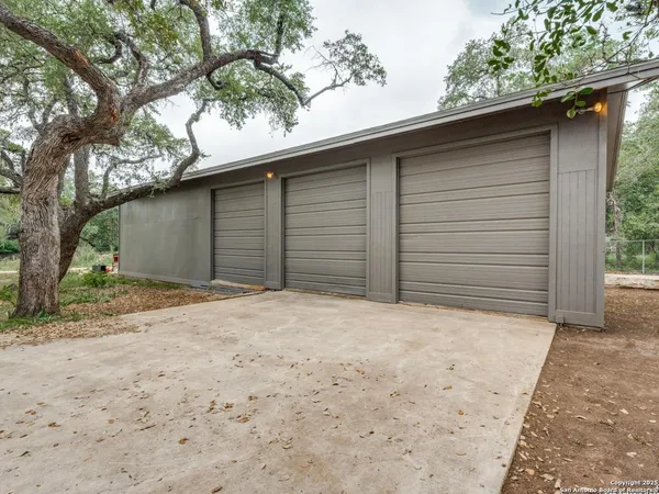 a backyard of a house with large trees and barbeque oven