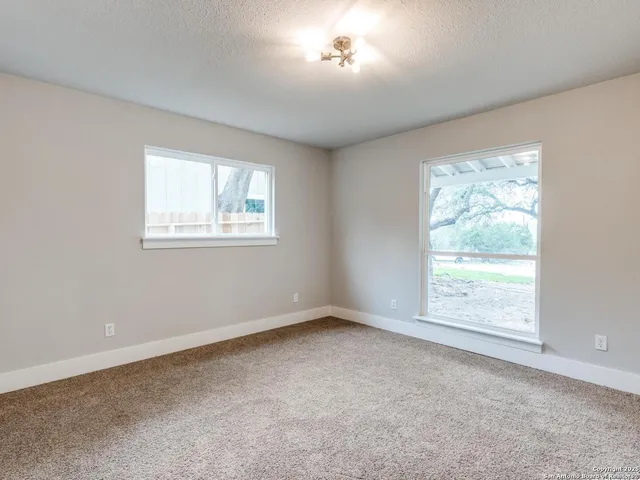 an empty room with wooden floor chandelier and windows