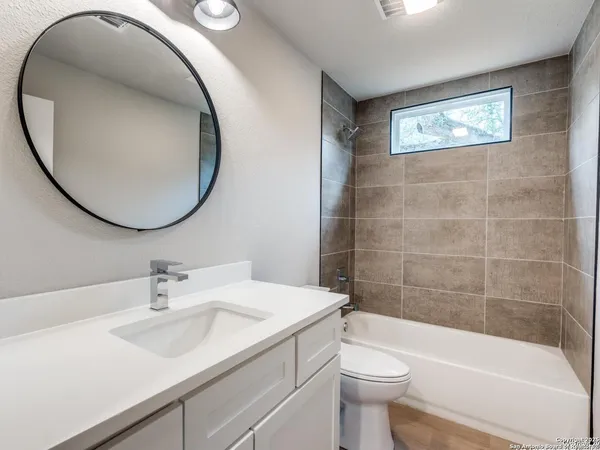 an empty room with a empty space a chandelier fan and windows