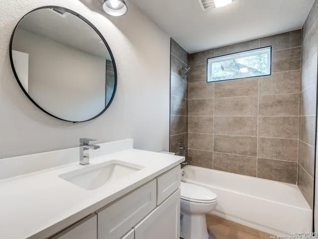 an empty room with a empty space a chandelier fan and windows