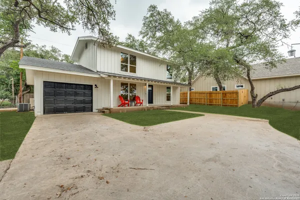a view of a white house with a big yard and large tree