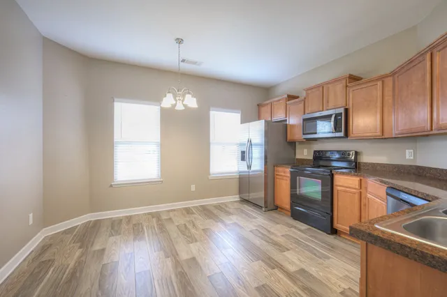 a kitchen with granite countertop a stove top oven a sink dishwasher a refrigerator and cabinets with wooden floor