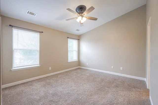 a view of an empty room and chandelier fan