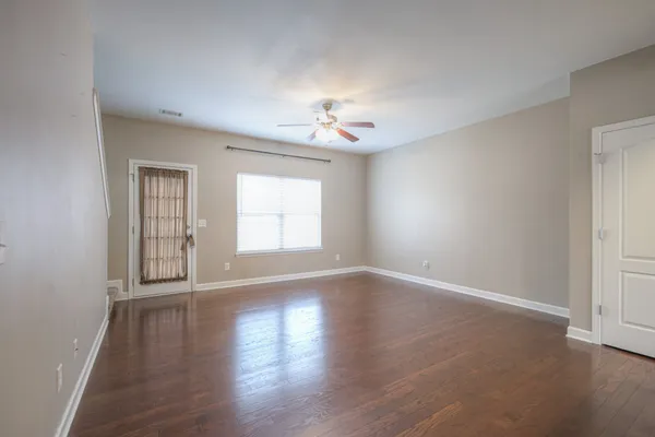 a view of an empty room with a window and wooden floor