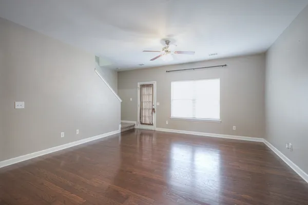 a view of an empty room with a window and wooden floor