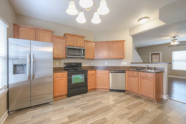 a kitchen with granite countertop a refrigerator stove top oven and sink