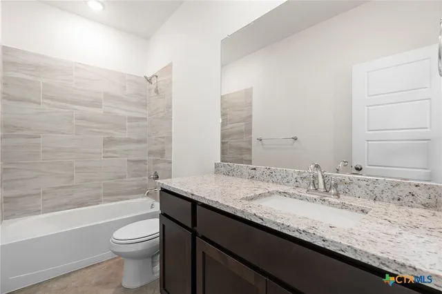 a bathroom with a granite countertop bathtub sink vanity mirror and toilet