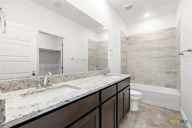 a bathroom with a granite countertop bathtub sink vanity and toilet