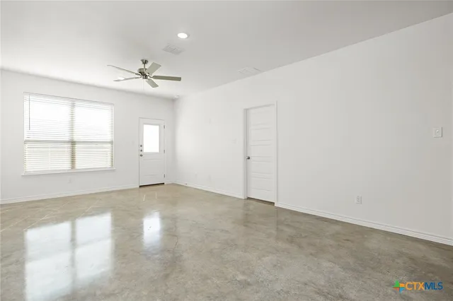 an empty room with windows and ceiling fan