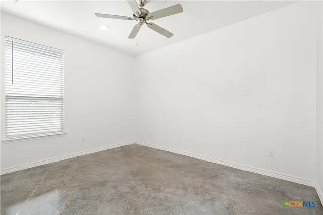 an empty room with a window and a fan