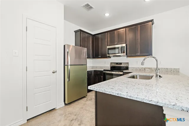 a kitchen with granite countertop a refrigerator and a sink
