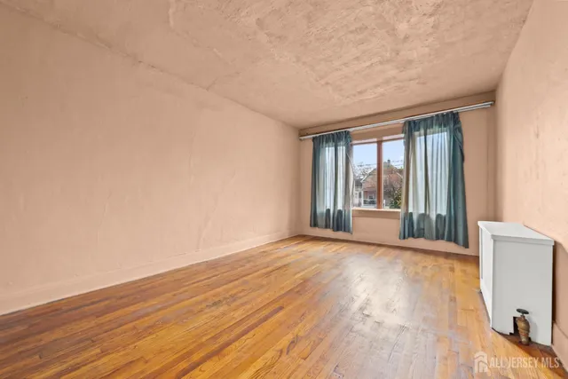 a view of an empty room with glass door and wooden floor