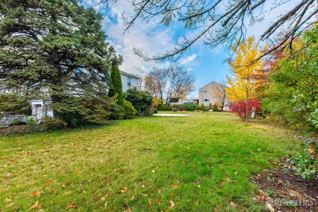 a view of a white house with a big yard and large trees
