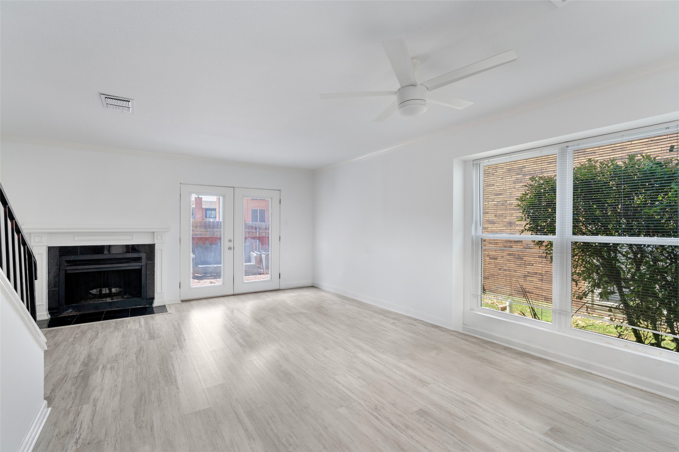 2018 West Rundberg Lane, Unit 16D Austin, TX 78758 - Photo 2 of 18 A spacious living area features a charming fireplace, light flooring, and French doors leading to an outdoor space.