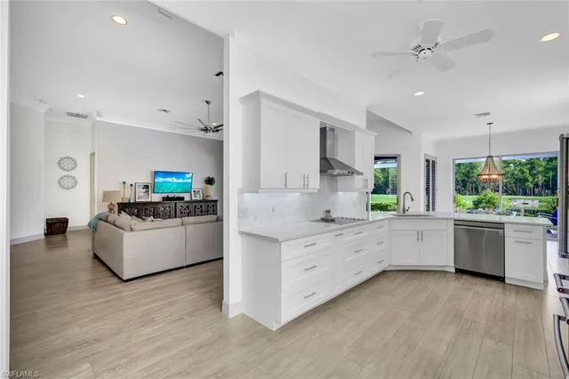 a large white kitchen with kitchen island white cabinets and stainless steel appliances