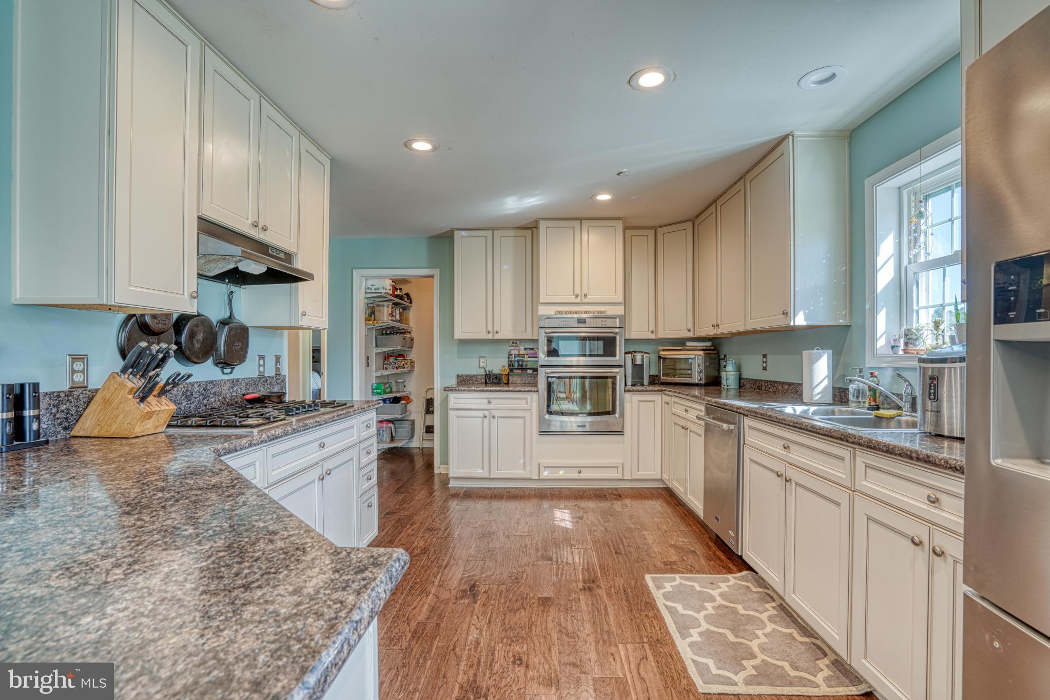 29862 Paddock Lane Easton, MD 21601 - Photo 31 of 83 a kitchen with stainless steel appliances granite countertop a stove top oven a sink a refrigerator and white cabinets with wooden floor