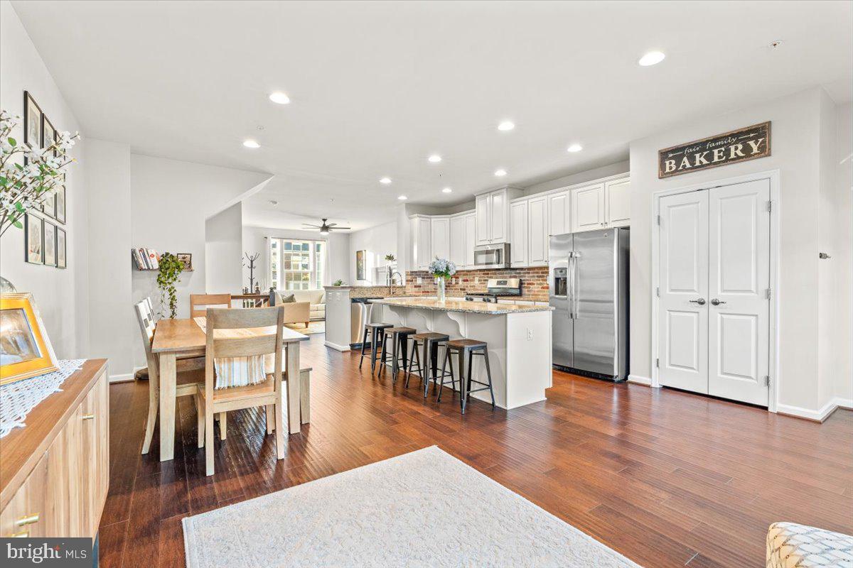 4535 Tinder Monrovia, MD 21770 - Photo 18 of 61 a open kitchen with kitchen island a refrigerator a stove a dining table and chairs with wooden floor