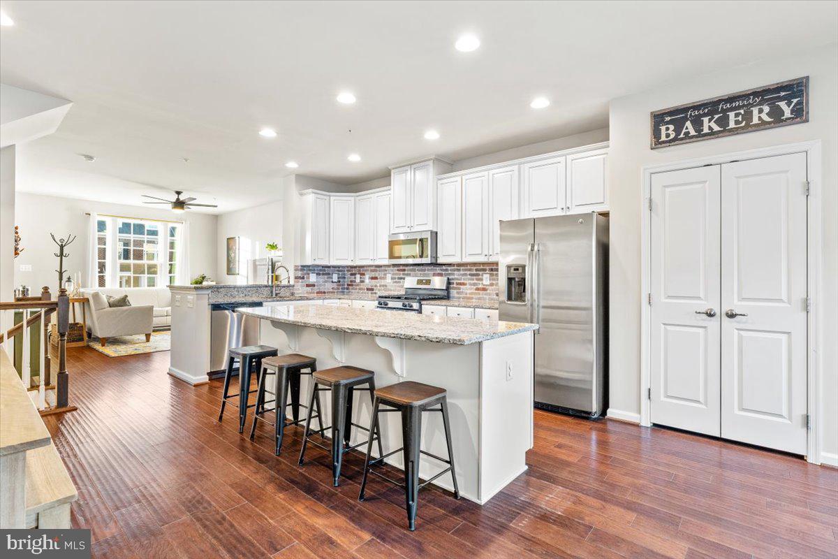 4535 Tinder Monrovia, MD 21770 - Photo 10 of 61 a kitchen with stainless steel appliances granite countertop a refrigerator a sink dishwasher a stove and white cabinets with wooden floor