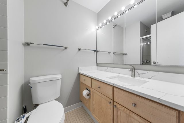 a bathroom with a granite countertop toilet sink and mirror