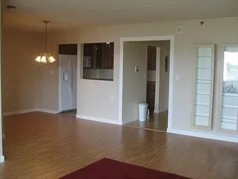 an empty room with wooden floor chandelier and windows