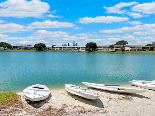 a couple of white and blue lawn chairs sitting next to a lake view