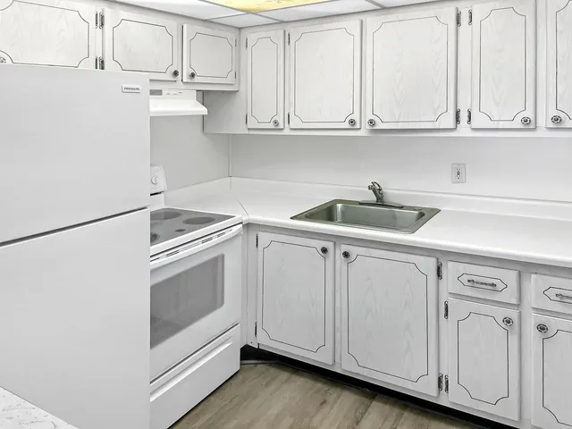 a kitchen with white cabinets and white appliances