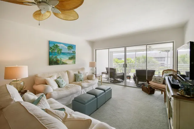 a living room with furniture ceiling fan and a large window