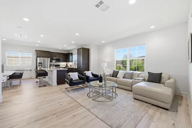 a living room with furniture kitchen view and a large window